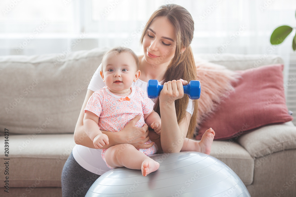 Young pretty mother working out with her little child at home Young pretty mother working out with her little child at home