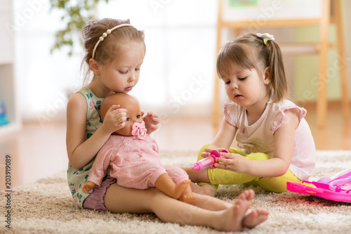 Valokuva children playing doctor with doll in playschool