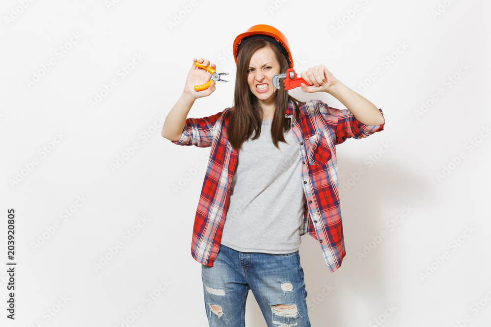 Irritated dissatisfied woman in casual clothes, protective construction helmet holding toy building tools isolated on white background. Instruments for renovation apartment room. Repair home concept. Irritated dissatisfied woman in casual clothes, protective construction helmet holding toy building tools isolated on white background. Instruments for renovation apartment room. Repair home concept.