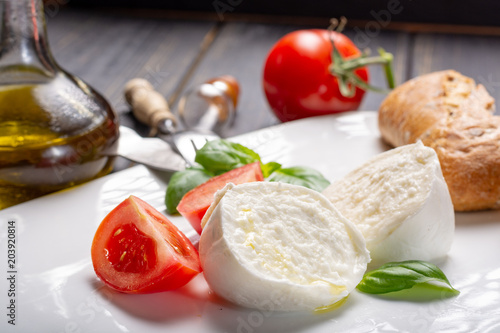 Traditional italian food - white ball mozzarella buffalo Italian soft cheese with cheese knife, tomato, basil, olive oil