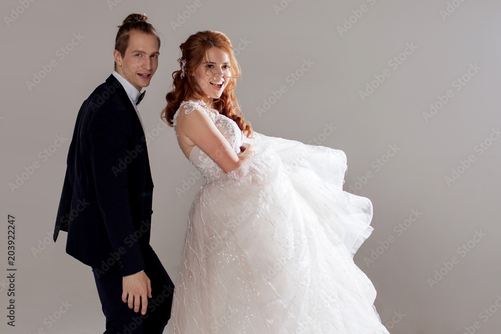 Positive young couple laughing and dancing together. The couple in the Studio a light background. Positive young couple laughing and dancing together. The couple in the Studio a light background.