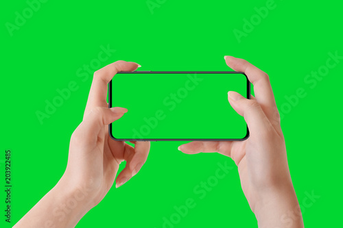 Female hands holding phone in horizontal position, isolated on green background