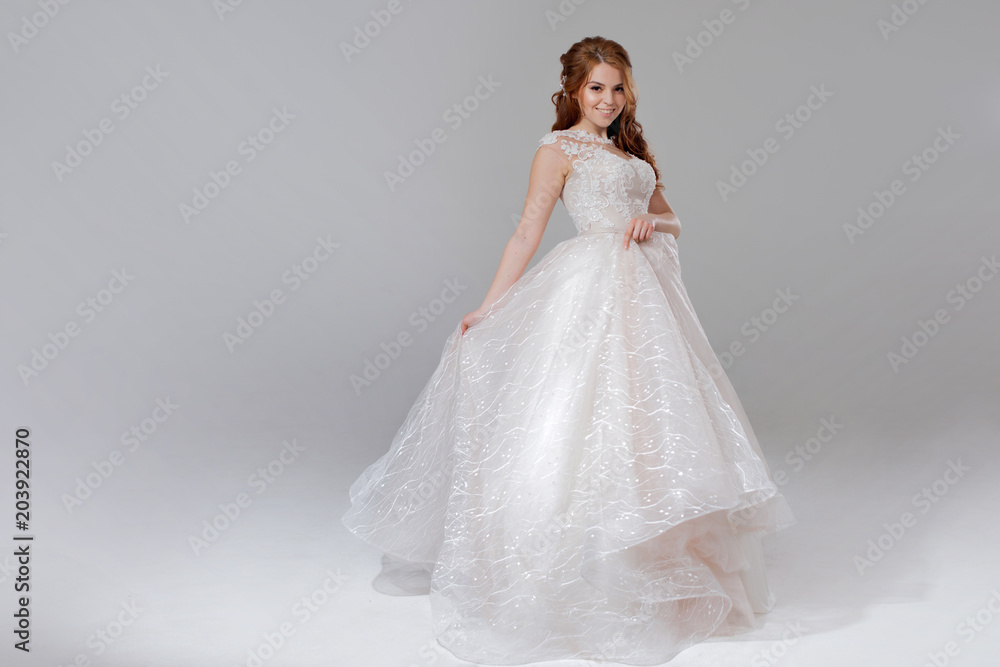 Lovely young woman bride in lavish wedding dress. Light background. Lovely young woman bride in lavish wedding dress. Light background.