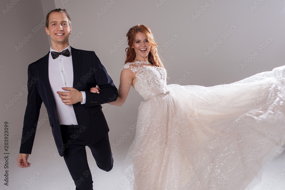 Positive young couple laughing and dancing together. The couple in the Studio a light background. Positive young couple laughing and dancing together. The couple in the Studio a light background.