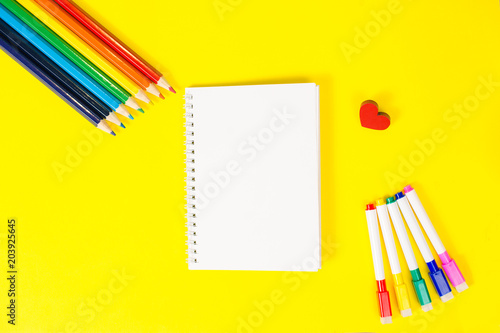 Top view concept of education, first of September back to school with pencils, blank notepad yellow background
