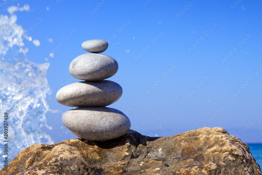 Spa stones balance on beach and sea waves crashing . Spa stones balance on beach and sea waves crashing .