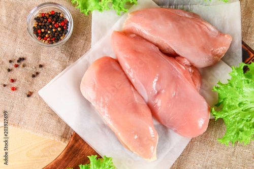 raw chicken fillets on wooden cutting board.