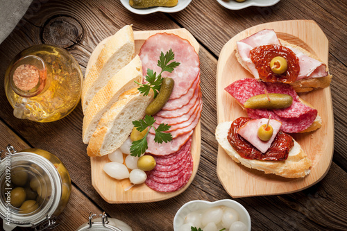 Tapas with sliced sausage, salami, olives and parsley.