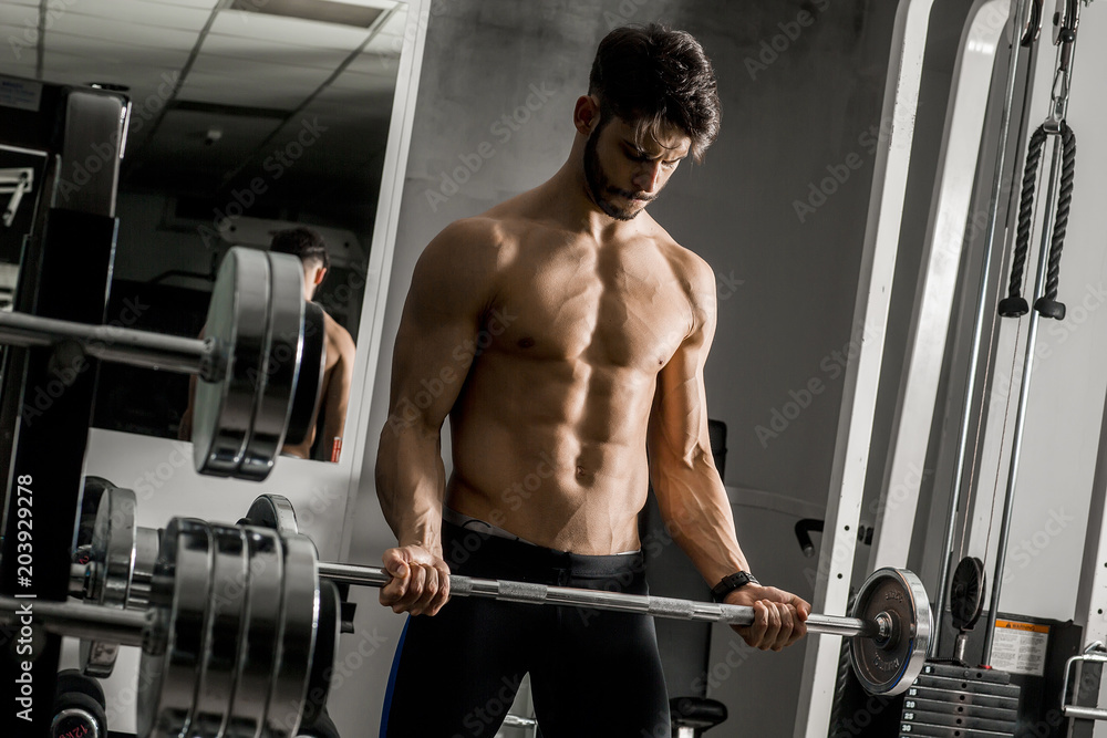 Strong and handsome young man doing exercise with dumbbells