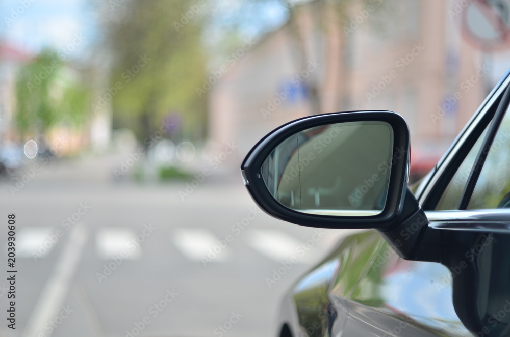 Car rear view mirror on the city background.