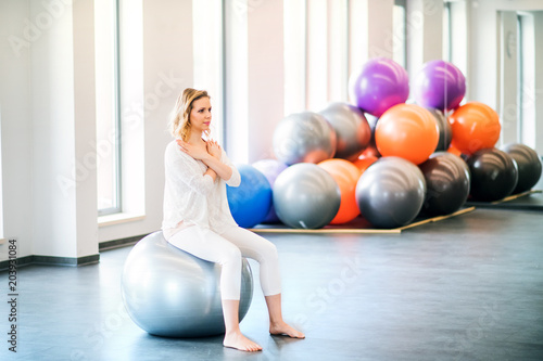 Young woman doing exercise with a fitball in a gym.