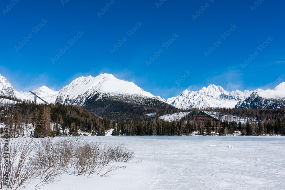 Slovakia, Strbske Pleso: View of frozen lake in Big Tatra, Slovakia. Mountains in background, the trees and lake in foreground. Winter and snow. Sport vacation and tourism.