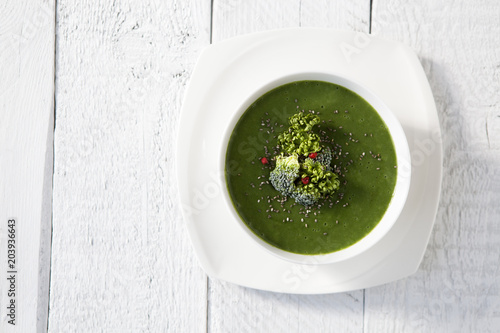 Spinach green soup with broccoli in white bowl top view