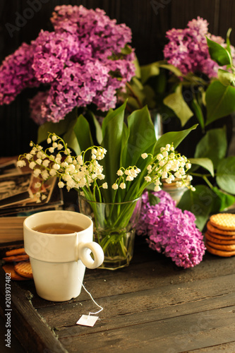 A cup of hot tea and a bouquet of lilac flowers (a date) Food background