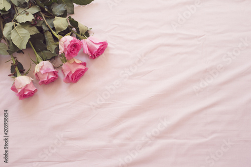 Floral frame with stunning pink roses on pink bed sheets in the bedroom. Copy space. Wedding, gift card, valentine's day or mother's day background