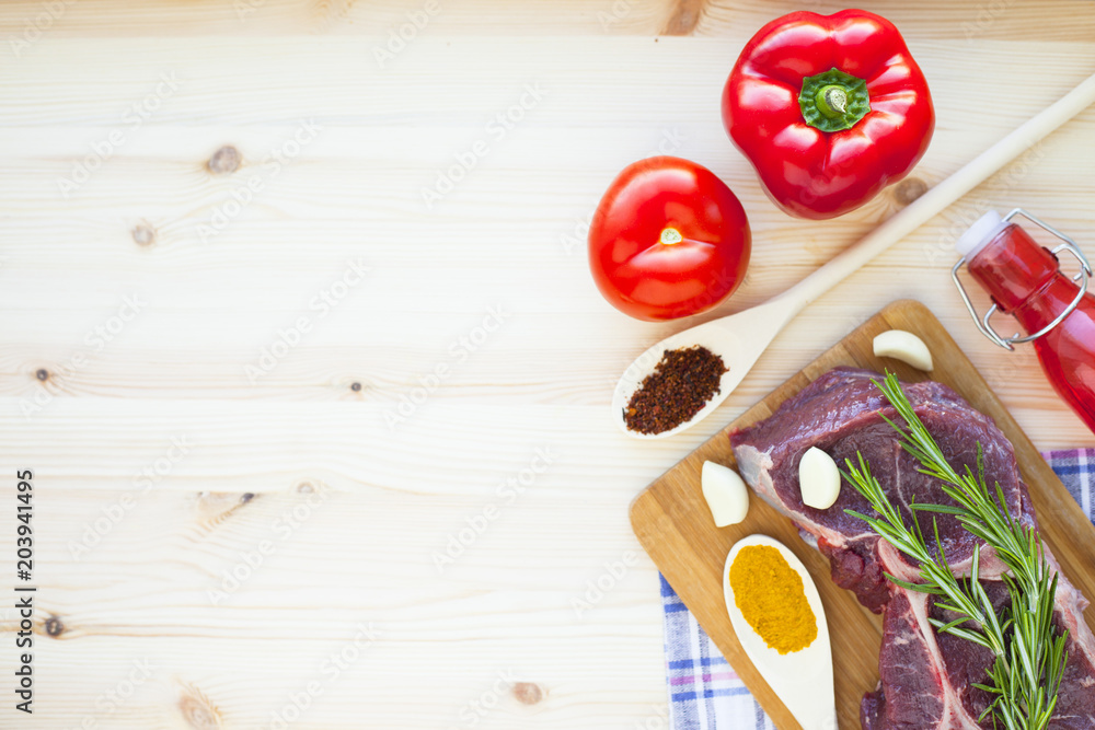 Raw beef meat on the wooden cutting board with vegetables, rosemary and spices. Top view. Close up. Food concept. Raw beef meat on the wooden cutting board with vegetables, rosemary and spices. Top view. Close up. Food concept.