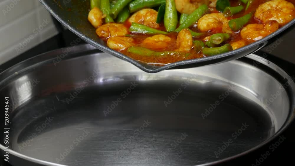 pour stir fried yard long beans with shrimp , kaffir lime leaves, spices curry paste from the black teflon pan to the stanless dish.
