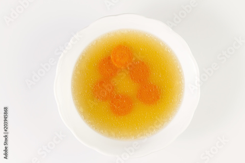 Clear beef broth with carrot slices. bone broth. Bouillon in white bowl.Isolated on white.