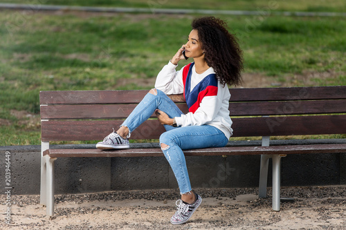 Trendy woman having phone call on bench