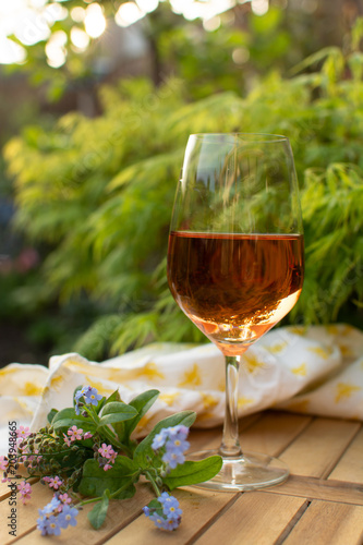 Trendy orange wine served on outdoor terrace in garden with flowers