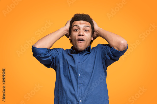 The young attractive man looking suprised isolated on orange