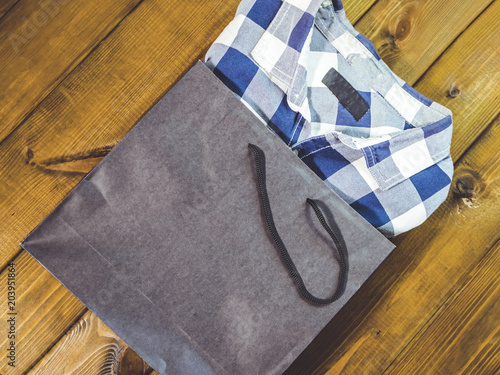 new checkered shirt pop out from shopping bag on a wooden background