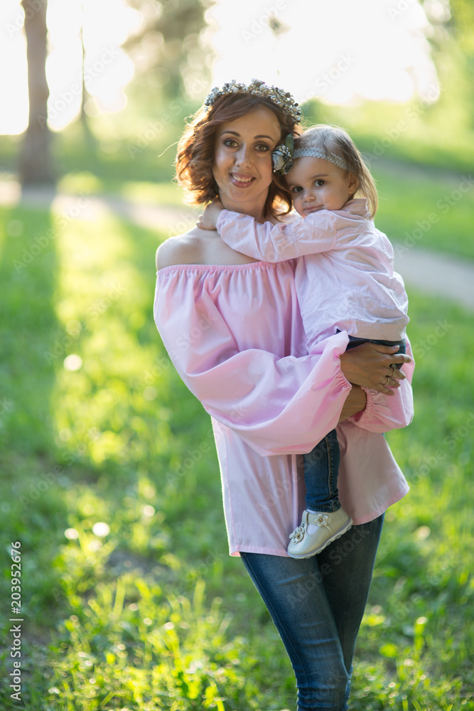 Mom and daughter are two years old sitting on the grass in the park