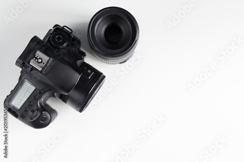 top view of modern photo camera and lens over white table