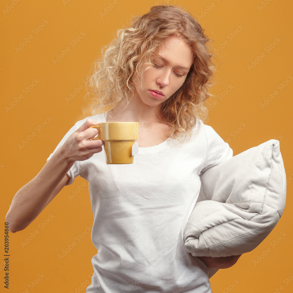 Sleepy girl with a cup of tea and a pillow on a yellow background. Sleepy girl with a cup of tea and a pillow on a yellow background.