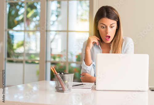 Student woman at table with laptop at home scared in shock, expressing panic and fear © Krakenimages.com