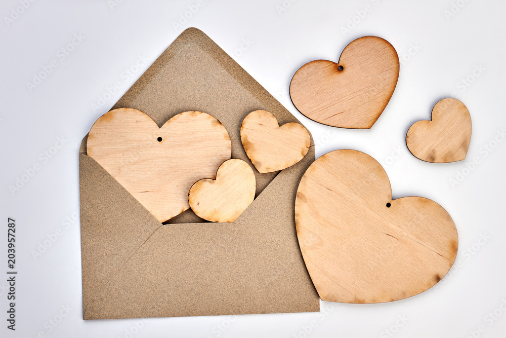 Obraz premium Opened envelope and plywood hearts. Vintage style envelope and wooden hearts on white background. Happy Valentines Day.