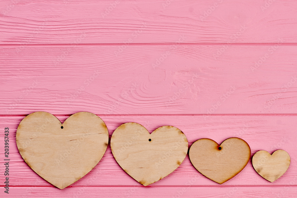 Obraz premium Row of wooden hearts and copy space. Four plywood blank hearts on pink wooden background, text space. Happy Valentines Day.
