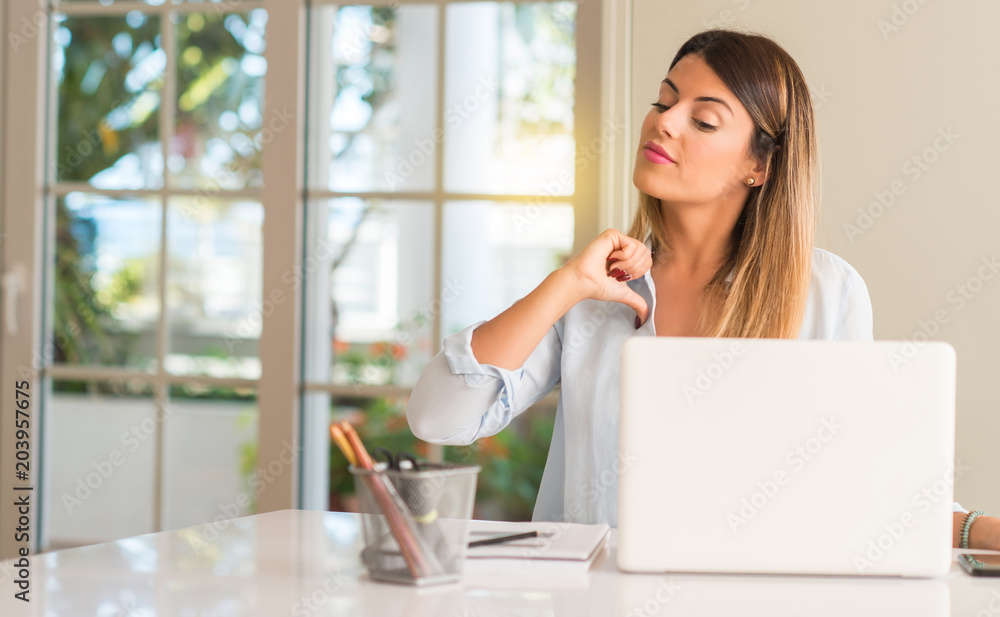 Student woman at table with laptop at home proud, excited and arrogant, pointing with victory face Student woman at table with laptop at home proud, excited and arrogant, pointing with victory face