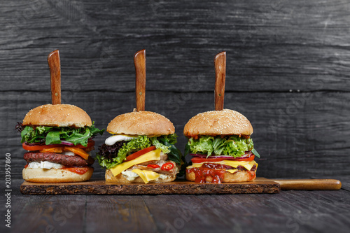 Delicious fresh hamburgers served on wooden plank with knife
