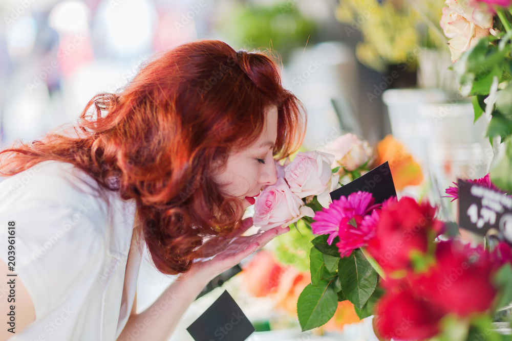 Naklejka premium woman smells at flowers of a flower shop