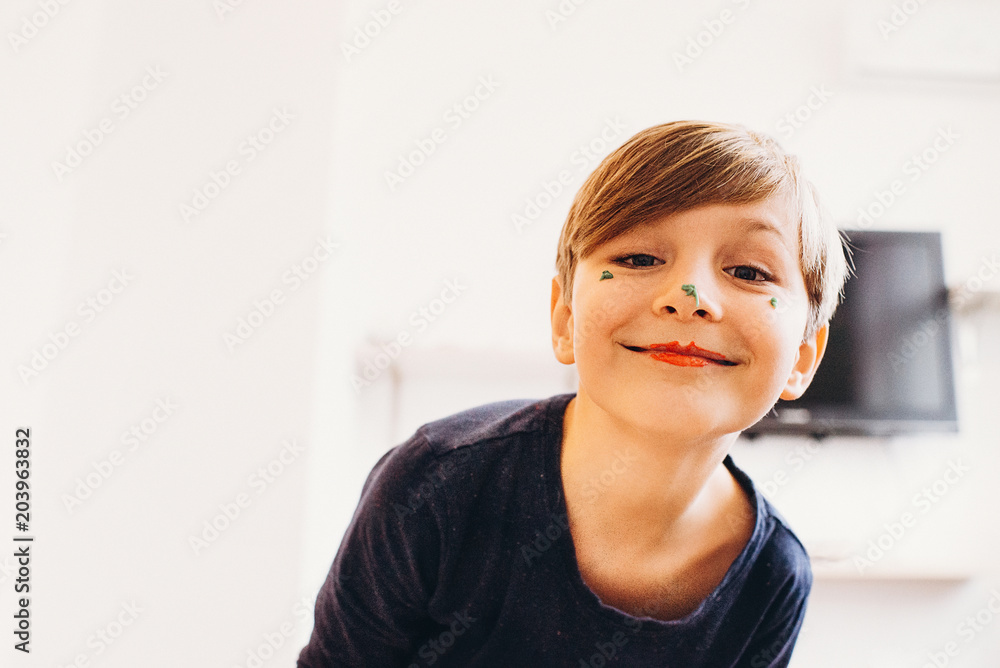 a closeup view of a cute boy with a face painted with eatable bright color cream, smiling with clown lips, soft focus, grain film texture image a closeup view of a cute boy with a face painted with eatable bright color cream, smiling with clown lips, soft focus, grain film texture image