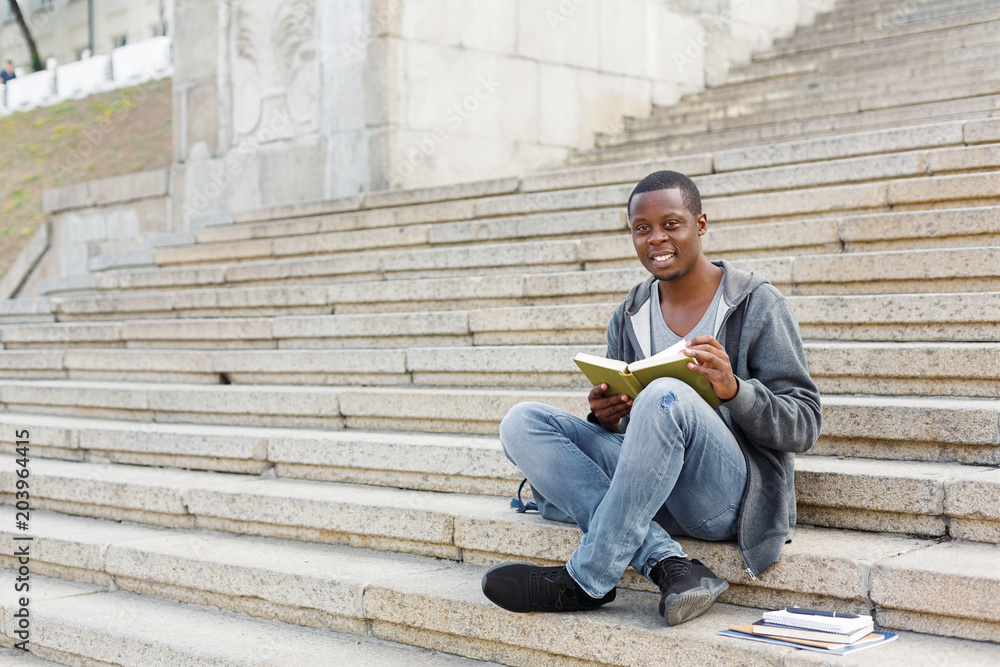 Young man reading book in campus copy space Young man reading book in campus copy space