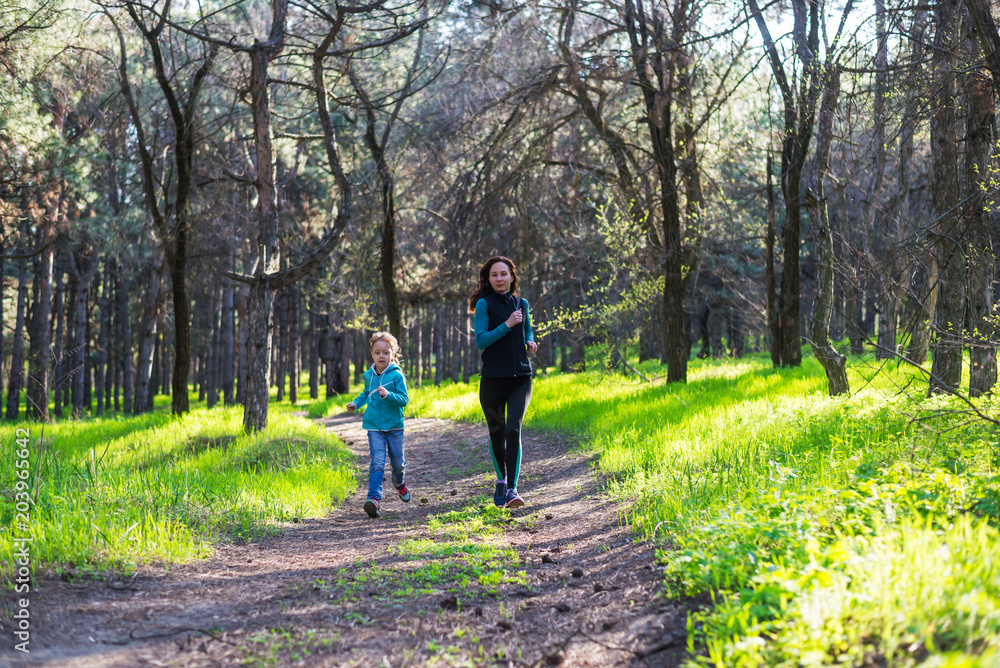 Morning jogging, mom and daughter are running along the forest trail, free space. Morning jogging, mom and daughter are running along the forest trail, free space.