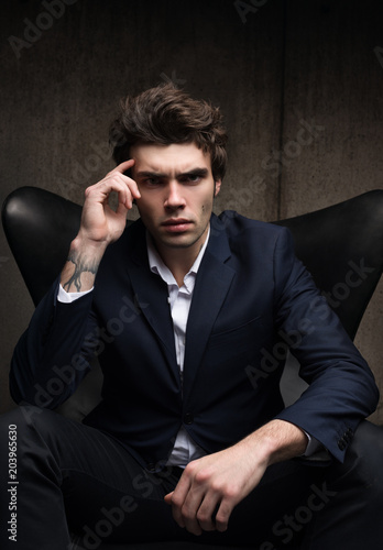 Business portrait of a serious young man sitting in a chair.