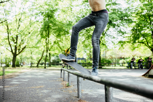 Unrecognizable shirtless skateboarder jump on a ramp.