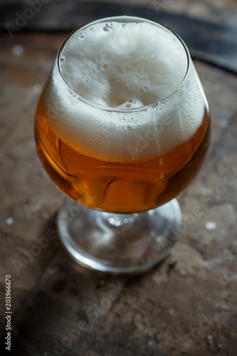 Snifter beer glass on a wooden barrel