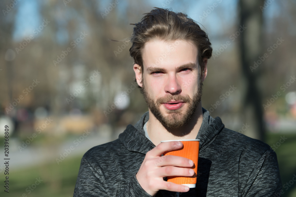 Bearded man with takeaway drink on fresh air. Macho hold disposable coffee cup in sunny park. Coffee or tea mood. Drink and food outdoor. Morning tea for breakfast Bearded man with takeaway drink on fresh air. Macho hold disposable coffee cup in sunny park. Coffee or tea mood. Drink and food outdoor. Morning tea for breakfast
