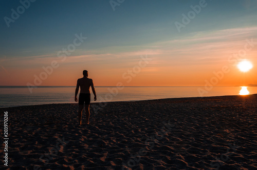 silhouette of man staring at the sea at sunset