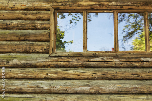Wooden log wall and window of the farmhouse ideal for background.