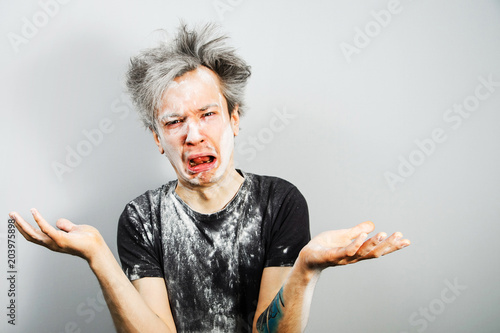 Fényképezés Unshorn and unshaven young guy soiled in plaster or flour and cry, on gray background