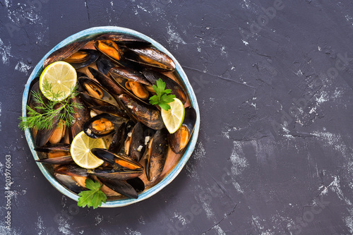 Boiled mussels in wine sauce on grey concrete background. Top view, copy space.