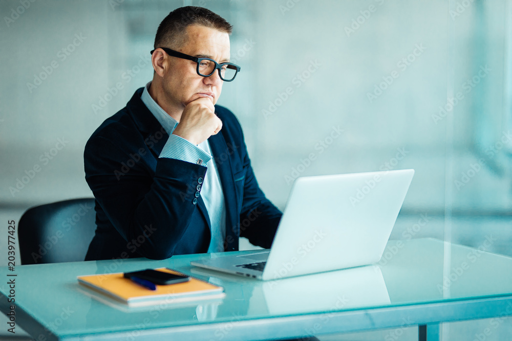 Senior man in modern office working on laptop computer Senior man in modern office working on laptop computer