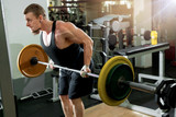 handsome young man exercising with a barbell in the gym