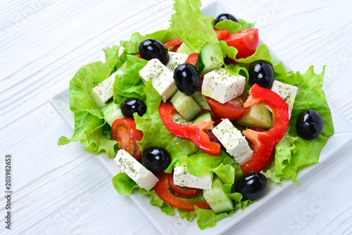 Greek salad on a white wooden background. Space for text or design.
