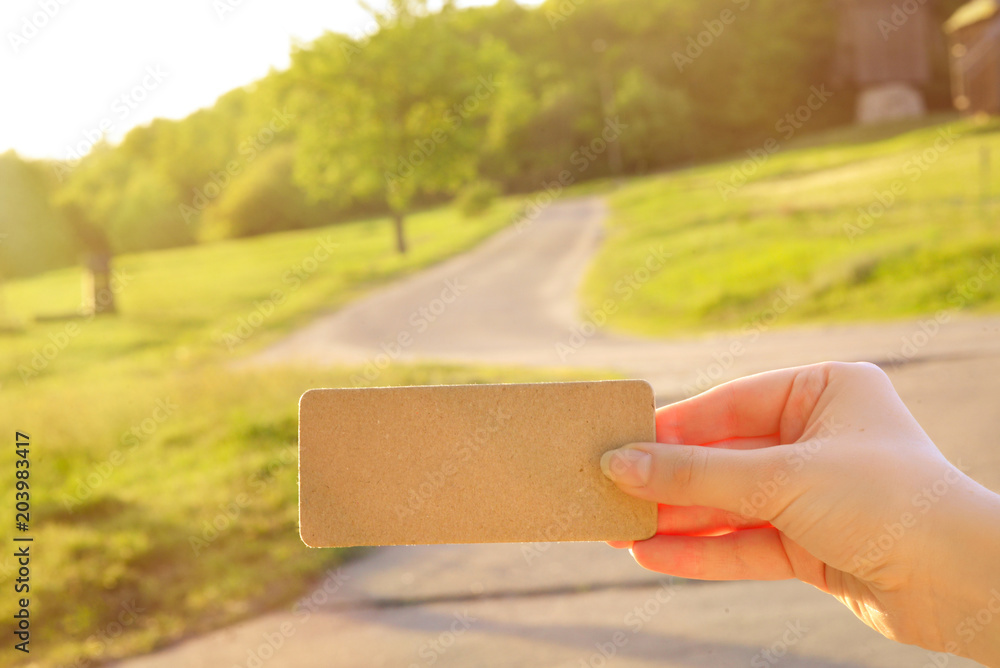 Girl holding empty card in a field with windmills and a road in sunny rays. Space for text. Girl holding empty card in a field with windmills and a road in sunny rays. Space for text.